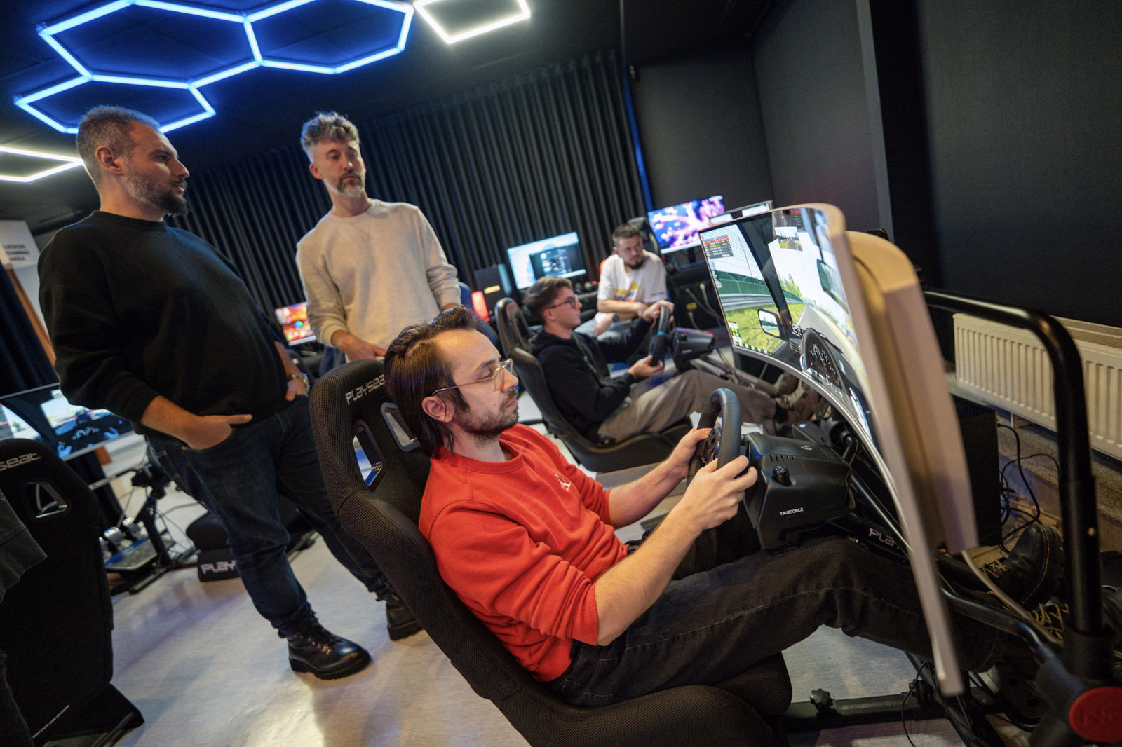 Participanți la două simulatoare de curse Gateway, cu volane și monitoare ultrawide